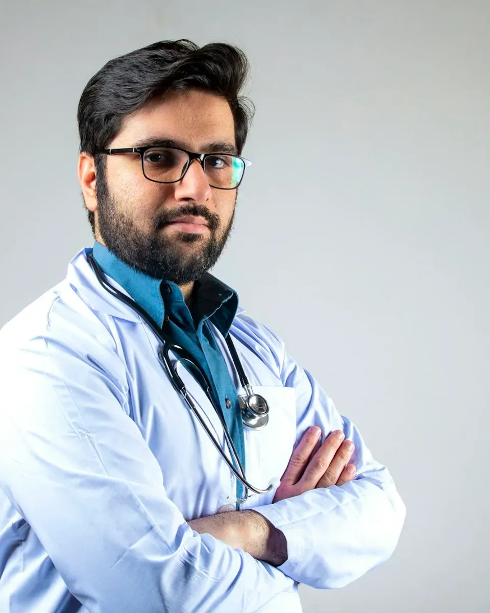Médico com jaleco e estetoscópio, de braços cruzados